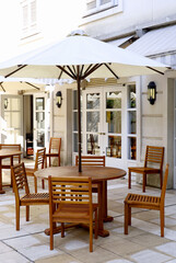 Wooden cafe tables and chairs with parasols line the courtyard, which is designed mainly in white