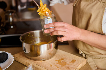 Person preserving food in jars wearing an apron in a kitchen setting