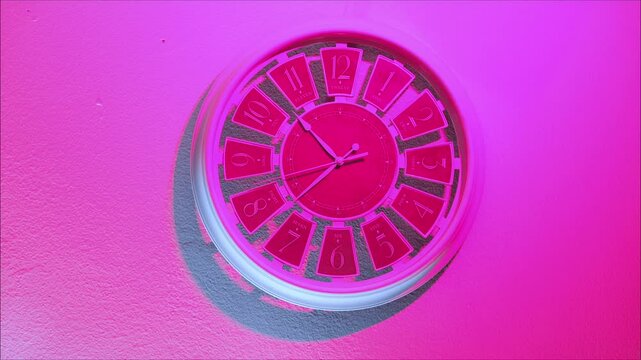 A white wall clock with a retro design, illuminated by white and neon pink light. Timelapse video. Rewinding time, a journey through the past, and retro style &ndash; a minimalist concept.