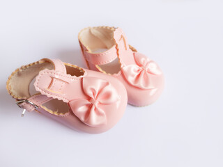 Delicate pastel pink shoes for a baby girl, newborn girl on a white background with copy space - ideal accessory for her first celebrations or as a keepsake.