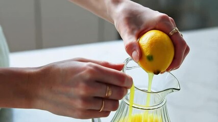 Fresh lemon being hand-squeezed into a glass pitcher, close-up of natural citrus juice preparation
- Powered by Adobe