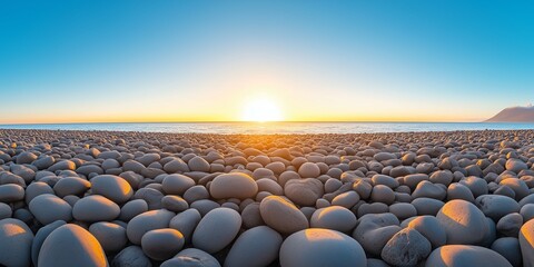 Fototapeta premium A stunning scene of a pebble-covered beach at sunrise, with smooth stones reflecting the golden hues of the morning light.