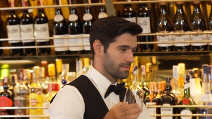 Good looking bartender chilling glass with ice for serving customer at beverage bar counter of welcome drink with charm professionalism, making great first impression warm smiling greeting. Vinosity.
