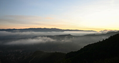 Misty valleys seen from the top of a mountain with a view of the silhouette mountains in rural Catalonia in Spain over a sea of clouds