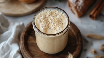 A glass jar with active, bubbly sourdough starter on the top. Homemade bread baking
