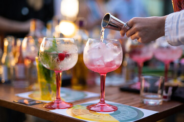 the bartender prepares a refreshing cocktail by pouring alcohol into a glass with ice