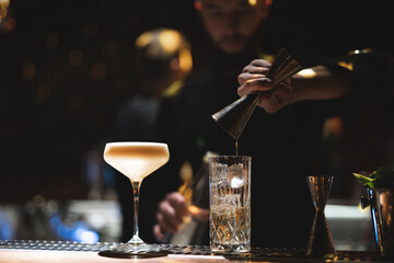 the bartender prepares a beautiful alcoholic cocktail at the bar counter