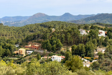 Fototapeta premium Spanish villa in suburb, aerial view. House in rural, view from mountain. Countryside with village houses near farm field. Rural landscape. Villa with garden. House roof in countryside in mountains.