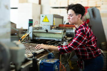 Woman monitors work of the conveyor for planting seeds in trays