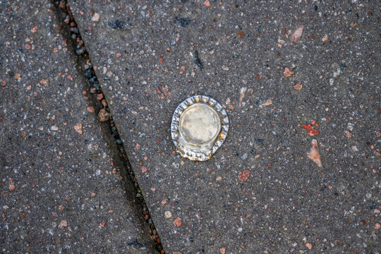 Flattened flast metal cap on stone floor.