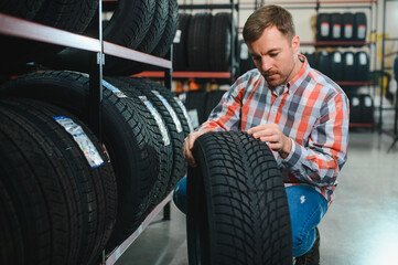 Portrait young man customer examining brand and product characteristics while buying new tires in...