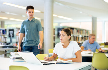 Smart female American student preparing for the exam in the school library
