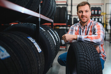Portrait young man customer examining brand and product characteristics while buying new tires in auto department of dealership. Male client choosing car accessories shopping mall © Serhii