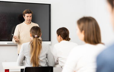 Competent male tutor teaching students in college classroom