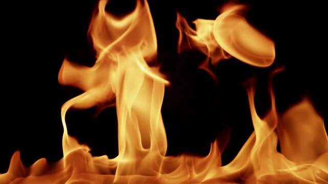 Beautiful dancing fire, the surface is ablaze. Lots of fire. Close-up immersion in the flames. The camera passes through the fire. Burning tongues of flame on a black backdrop in slow motion. 4K.