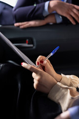Car dealership salesperson preparing purchase paperwork and documentation after agreeing terms with customer during test drive. Close up of showroom employee giving sale contract for client to sign
