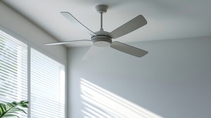 Modern ceiling fan with five blades in a bright room with sunlight streaming through white blinds.