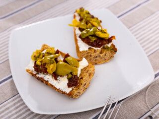 Appetizer bruschetta with sun-dried tomatoes, olives and cheese
