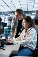 Worker requesting help from senior engineer to fix error in high tech AI data center. Employee in...