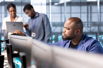 Computer scientist in data center workspace using diagnostic tools and system monitoring software...