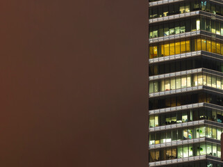 Obraz premium Steel and glass skyscraper buildings illuminated at night, of homes and offices, with copy space