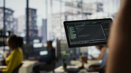 Data scientist uses tablet to check on machine learning models that can analyze data to automate...