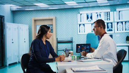 Medical expert and patient meeting at a check up appointment to discuss lab test results and potential treatment for recovery. Healthcare industry with medical insurance services. Camera A.