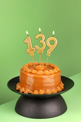 Delicious cake with dulce de leche - Number 139 birthday candle on a green background.