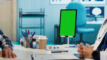 Female general practitioner and patient looking at green screen on tablet, recommending pills and drugs during check up. Indian people discussing about diagnostic report and remedy. Camera A.