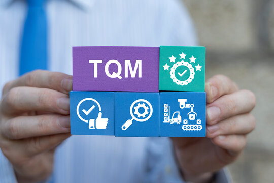 Business person holding colorful blocks sees abbreviation: TQM. Total Quality Management (TQM) Business Concept. Management approach to long-term success through customer satisfaction, sustainability.