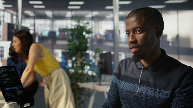 System administrator doing software quality assurance, checking source code on tablet. Close up of african american IT specialist at work inspecting coding on device, looking to fix errors, camera B