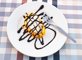 Portion of an appetizing sponge roll with a curd cream filling, drizzled with jam on top