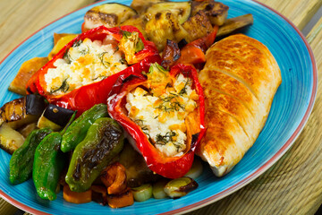 Tasty different baked vegetables at plate with stuffed peppers and chicken fillet