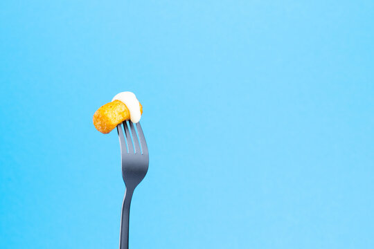 Potato pampushka french fries on a black fork on a blue background