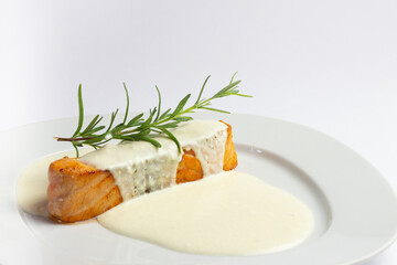 Salmon steak with sauce and rosemary on a white platem