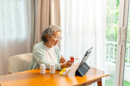 Telemedicine, telehealth technology and medical healthcare in elderly people at home. Asian senior woman video call with doctor on digital tablet consultation with medicine, drugs and supplements.