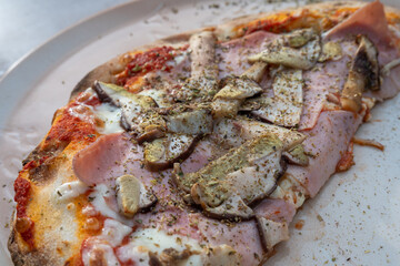 Close up view of freshly baked seasonal pizza with ham, porcini mushrooms and cheese
