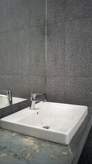 A spotless and modern wash basin with a sleek design, equipped with a clean faucet and mirror. Ideal for public or private spaces, ensuring hygiene and convenience for washing hands or face.