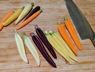 Assorted rainbow carrots on wooden cutting board with knife