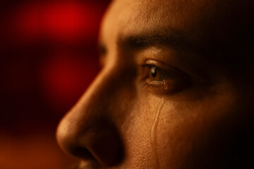 Closeup portrait of a crying mans face with tears running down his cheek.