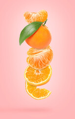 Ripe juicy tangerines falling on pink background