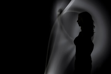 Obraz premium Silhouette of a Woman with Abstract Light Trails in Dark Minimalist Composition