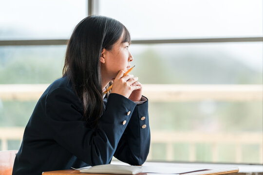 授業中に外を眺める中学生の女子生徒（進路・夢・思春期）
