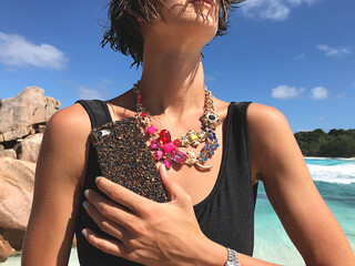 Woman holding glamorous phone standing on the beach 