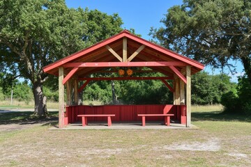 Charming Open Pavilion in a Scenic Park Surrounded by Lush Green Trees and Clear Blue Sky, Perfect for Family Gatherings, Events, or Relaxation in Nature's Splendor