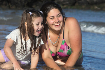 Fototapeta premium young hispanic mother and her little daughter in the water at the beach on sunny summer day