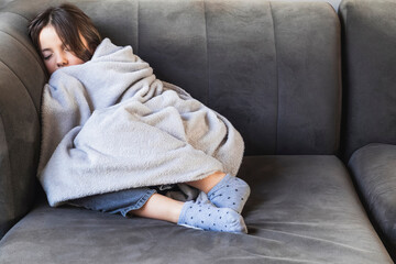 Girl sleeping on sofa covered with blanket during winter time