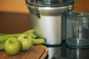 Green apples and celery on kitchen bench with juicer
