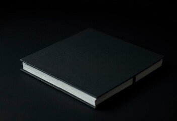 A minimalist black book with a blank cover rests on a dark surface, creating an elegant mockup suitable for design projects and presentations.