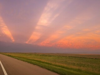 Colorful sunset sky over open Kansas prairie landscape with sunlight streaking through